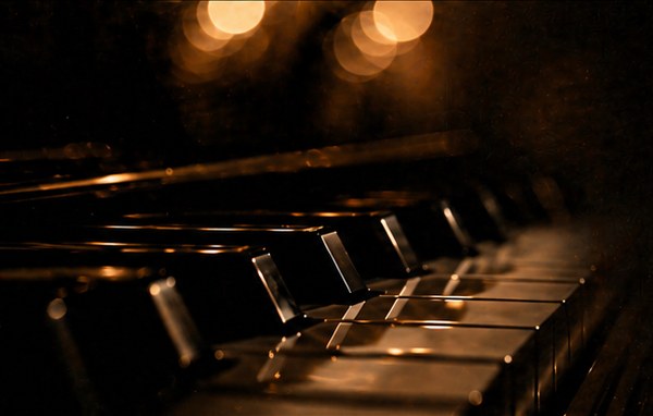 Close-up of grand piano keys glowing in amber light